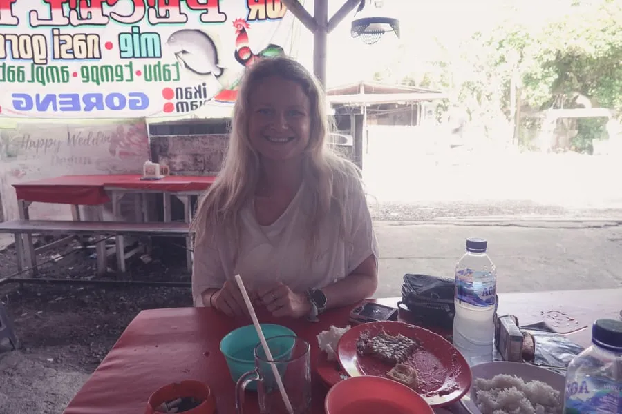 Tine duduk di meja merah dengan makanan yang disajikan di piring kecil.